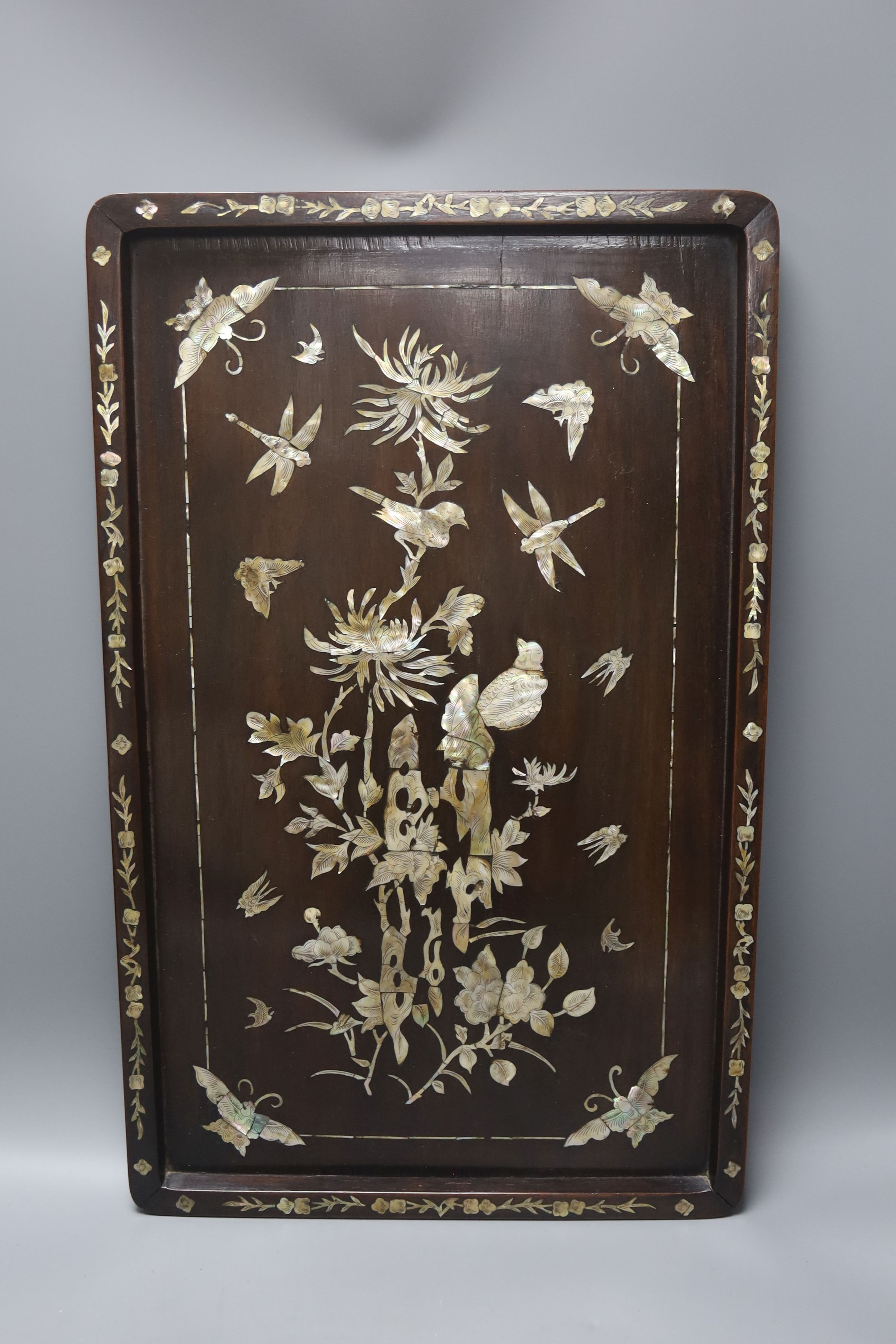 Two Chinese mother of pearl inlaid hongmu trays, the rectangular example with birds and insects amid flowers and the smaller oval example with a pavilion in a landscape within floral sprays 55x34cm